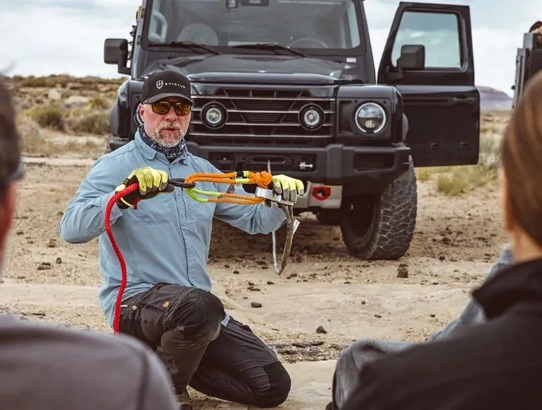 Instructor demonstrating a winch remote in front of a 4x4 as guests watch